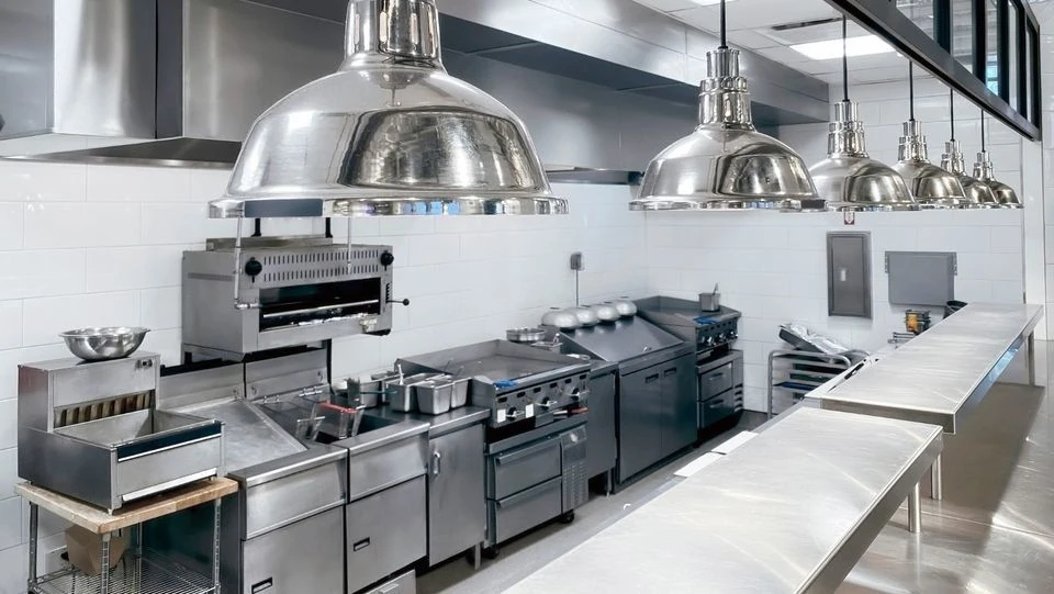 Cocina industrial equipada con mobiliario y campanas de acero inoxidable